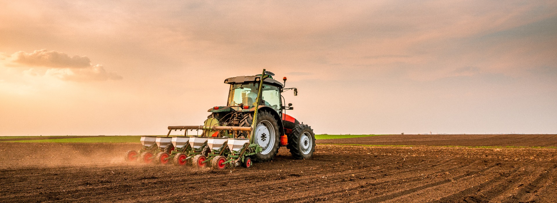 Tractor drilling seeding crops at farm field. Agricultural activity.